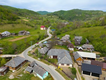Rural village view with roads and traditional houses in a hilly green landscape, aerial view,
