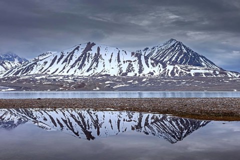 Reflection of mountains in lake near the Fjortende Julibreen, 14th of July Glacier in spring,