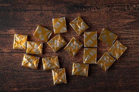 Several soup cubes in golden packaging on a wooden table