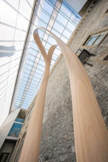 Close-up of a modern sculpture in front of stone walls under a glass roof, National Gallery of