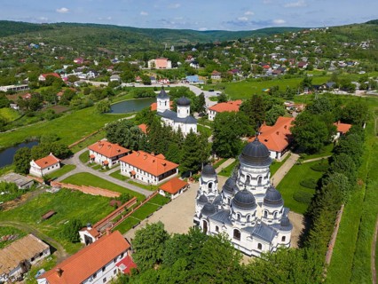 Aerial view of a monastery with Orthodox churches in a green landscape surrounded by forests,