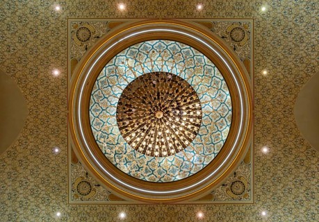An upward view of a crystal chandelier hanging from the intricately decorated geometric dome, Qasr