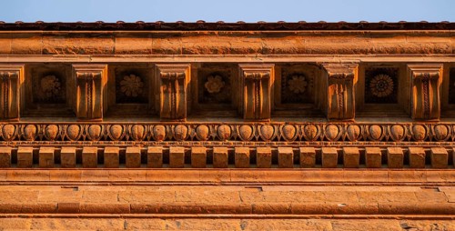 Detailed view of the intricately crafted roof cornice of Palazzo Strozzi, warm evening light, old
