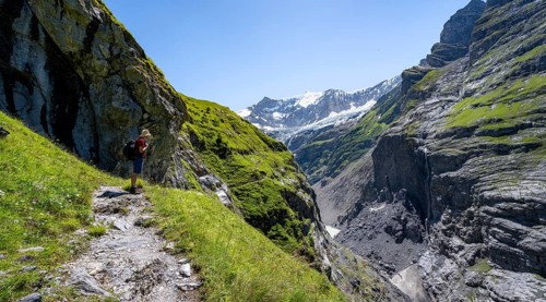 Mountaineers on a narrow hiking trail in a rocky gorge with waterfall, mountain landscape with