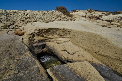 Ancient excavation remains, sandy and rocky formations on the coast in direct sunlight,