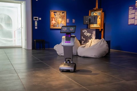 A robot with a fly in an exhibition in front of paintings, museum robot Robolutions in the