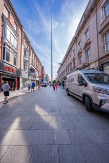 View of the city center with tall buildings, busy shopping street and the Spire in the background,