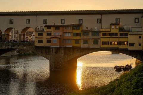Sun rays reflect on the Arno River, crowd on the historic Ponte Vecchio, evening mood, old town,