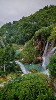 Cascading waterfalls in a green setting full of lush plants and rocky elevations, Plitvice Lakes