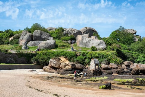 Distinctive, monumental pink granite rocks cut round by sea and wind on a stretch of beach near