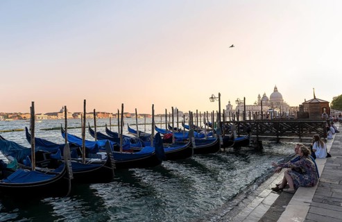 Tourists enjoying the evening, Venetian gondolas, boat launch at St. Mark's Square, Basilica Santa