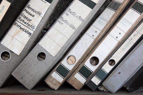 Office scene around 1982, lost place, abandoned location, classic file folders on a wooden shelf,