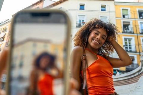 Young african american woman with curly hair smiling directly at the camera, posing for a selfie