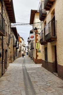 Typical narrow alley, historic stone houses with traditional wooden balconies, bar, cobblestones,
