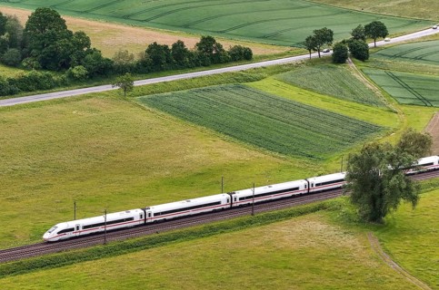 High speed on rails, everyday traffic on asphalt, a Deutsche Bahn ICE overtakes cars on the federal