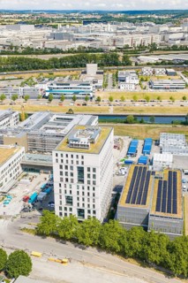 Commercial building with solar panels in a commercial area surrounded by green spaces, airfield,