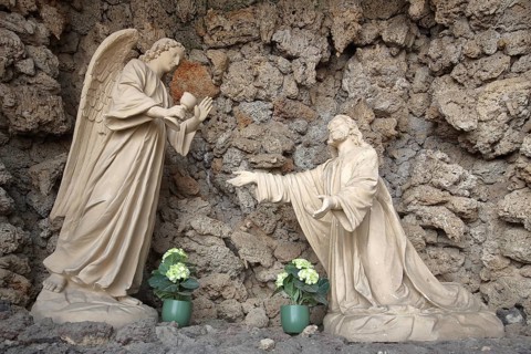 Angel presents golden chalice to Jesus, stone sculpture, biblical scene on the Mount of Olives,