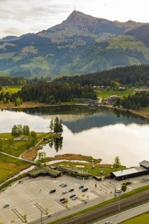 Panoramic view of a lake with mountains in the background and a parking lot in the foreground,