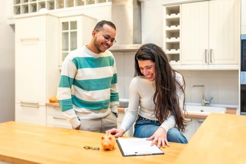 Happy young couple discussing financial plans, managing budget, and saving money together at home,