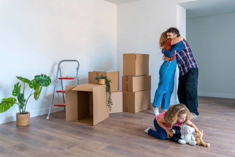 Happy family celebrating moving into a new home, parents embracing with love and joy surrounded by