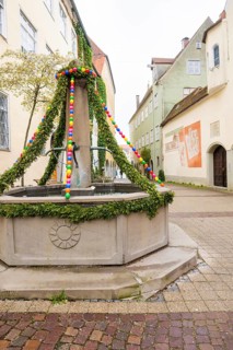 Decorated fountain in an old town alley with colorful garlands, Isny, Allgäu, Bavaria, Germany