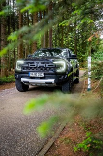 Car driving on a quiet forest road flanked by green vegetation, district service with Björn