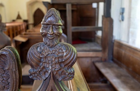 Carved wooden poppyhead face of man with beard, village parish church of Saint Andrew, Winston,