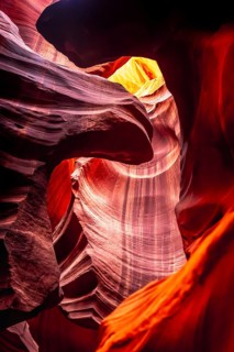 Antelope canyon winding sandstone walls with smooth, wavy erosion patterns, glowing opening above