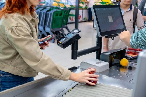 Young woman actively scanning fresh produce like an apple and a peach at a modern self service
