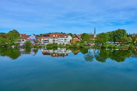 Picturesque village view with church whose reflection can be seen in the quiet river, Main,