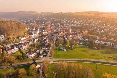 Village with church and green areas in hilly landscape at sunset, Deufringen, Aidlingen, Heckengäu