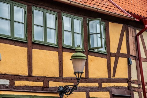 Part of the facade with windows and street lamp of an older half-timbered house in Ystad, Skåne