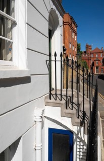 Details of a building with stairs and lattice door, narrow street lined with historic brick
