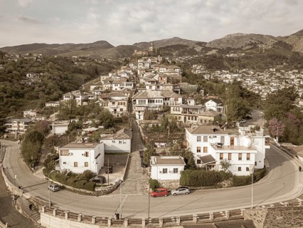 Aerial panoramic view massive stone Gjirokaster Castle on hilltop, surrounded by historic Stone