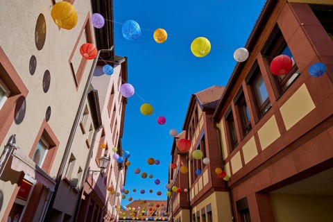 Bright colored lanterns decorate a narrow alley on a clear summer day, Lohr am Main,