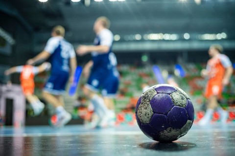 The handball ball laiyng on the parquet and handball match in the background in Lubin, Poland