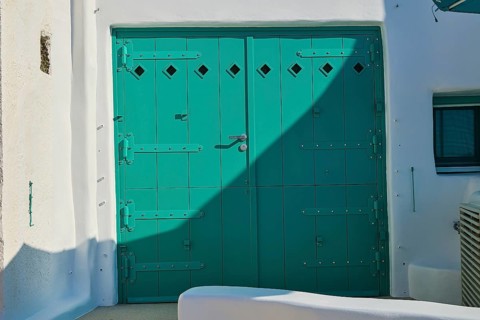 Close-up of green door in white building with shadow effect, Syrmata, boat garages, boathouse,