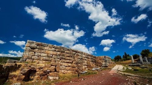 Stone wall under blue sky with dramatic clouds, ancient site, archaeological site, Messene,