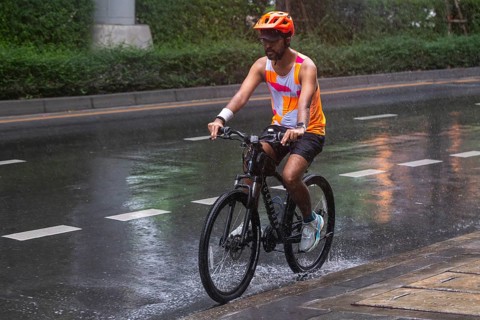 Cyclists in rain, Bangkok, Thailand
