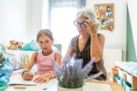 Grandmother assisting her young granddaughter with homework and learning activities, fostering
