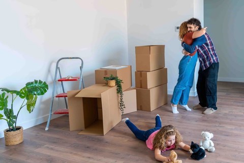 Young family celebrating relocation to a new home, parents embracing happily while their daughter
