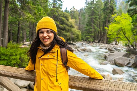 Woman standing on a wooden bridge, smiling confidently while enjoying the fresh air and natural