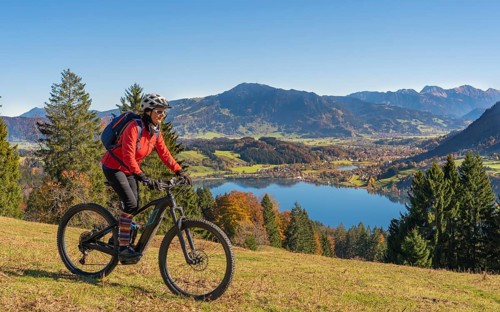 Senior woman riding her electric mountain bike in autumn on the mountains above the Alpsee near