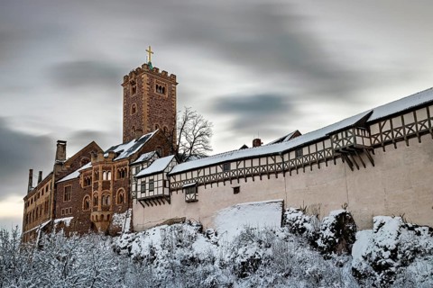 Wintery castle with snow-covered tower and timbering under cloudy sky, The Wartburg near Eisenach