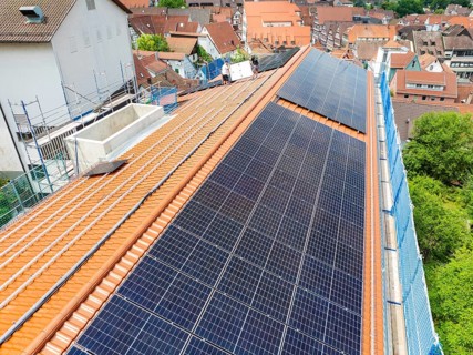 Solar module installation on tiled roof with urban background, new PV system at