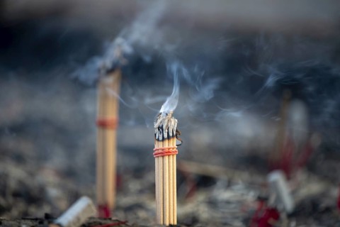 Fine smoke rises between the upright incense sticks and forms soft, swirling lines in the warm air.