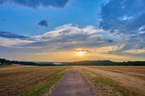 Small path leads through a field at sunset surrounded by a dramatic sky, summer, Reichartshausen,