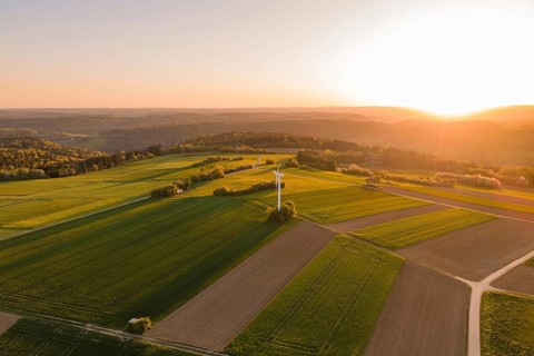 Large green fields with a wind turbine at sunset, vast and peaceful landscape, Jettingen, Germany