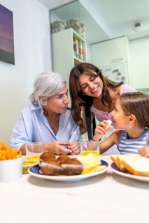 Grandmother, daughter, and granddaughter enjoying a joyful breakfast together in a bright kitchen,