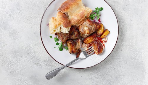 A plate with leftover pork kebab, with bread, on a white plate, close-up, there are no people